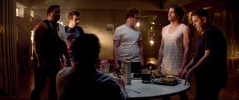 Movie still from “This Is the End” (2013), directed by Seth Rogen – A group of people standing around a table; Medium shot, Over the shoulder angle