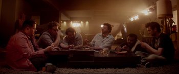 Movie still from “This Is the End” (2013), directed by Seth Rogen – A group of people sitting around a table; Medium shot, High angle