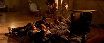 Movie still from “This Is the End” (2013), directed by Seth Rogen – A group of men sitting on the floor watching television; Wide shot, High angle
