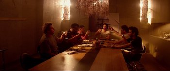 Movie still from “This Is the End” (2013), directed by Seth Rogen – A group of people sitting at a table eating food; Wide shot, Low angle
