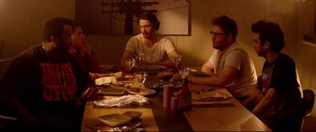 Movie still from “This Is the End” (2013), directed by Seth Rogen – A group of people sitting at a table with plates and wine glasses; Medium shot, Over the shoulder angle