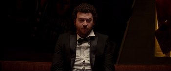 Movie still from “This Is the End” (2013), directed by Seth Rogen – A man in a suit and tie sitting in a chair; Medium shot, Low angle