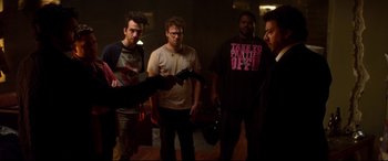 Movie still from “This Is the End” (2013), directed by Seth Rogen – A group of men standing around in a dark room; Medium shot, Over the shoulder angle