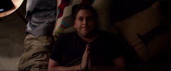 Movie still from “This Is the End” (2013), directed by Seth Rogen – A man is sitting on a pillow with his hands in prayer position; Medium shot, High angle