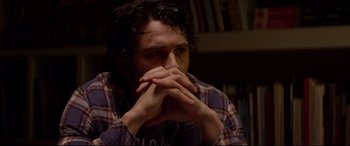 Movie still from “This Is the End” (2013), directed by Seth Rogen – A man sitting in front of a bookshelf with his hands over his face; Close Up shot, High angle