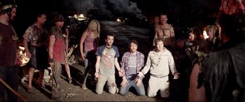 Movie still from “This Is the End” (2013), directed by Seth Rogen – A group of young people standing next to each other in front of a fire; Wide shot, High angle