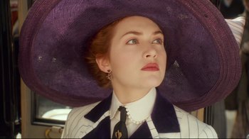 Movie still from “Titanic” (1997), directed by James Cameron – A woman wearing a purple hat and a suit; Close Up shot, Low angle