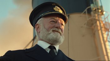 Movie still from “Titanic” (1997), directed by James Cameron – An old man with a beard wearing a hat and tie; Close Up shot, Low angle