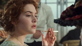 Movie still from “Titanic” (1997), directed by James Cameron – A person holding a cigarette in her mouth; Close Up shot, Over the shoulder angle