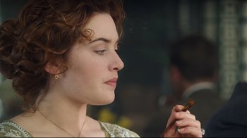 Movie still from “Titanic” (1997), directed by James Cameron – A person holding a cigarette in her hand; Close Up shot, Over the shoulder angle
