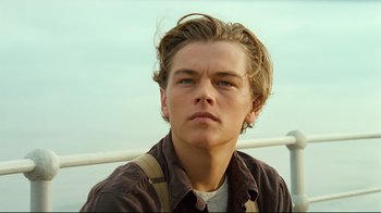 Movie still from “Titanic” (1997), directed by James Cameron – A young man with long hair and a brown shirt; Close Up shot, Low angle