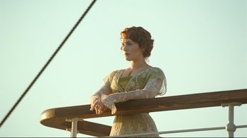 Movie still from “Titanic” (1997), directed by James Cameron – A woman standing on top of a wooden railing; Medium shot, Low angle