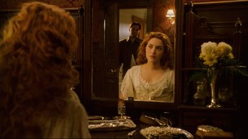 Movie still from “Titanic” (1997), directed by James Cameron – A woman looking in the mirror in front of a man in a suit; Medium shot, Over the shoulder angle