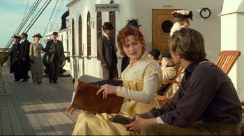 Movie still from “Titanic” (1997), directed by James Cameron – A woman in a yellow dress sitting on a bench; Medium shot, High angle