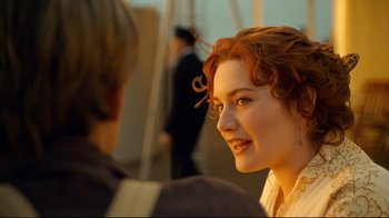 Movie still from “Titanic” (1997), directed by James Cameron – A woman with red curly hair smiling at the camera; Close Up shot, Over the shoulder angle