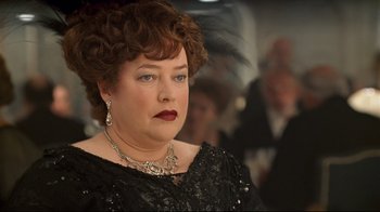 Movie still from “Titanic” (1997), directed by James Cameron – An older woman in a black dress and a feather necklace; Close Up shot, Over the shoulder angle