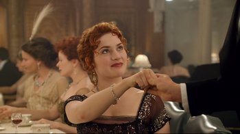 Movie still from “Titanic” (1997), directed by James Cameron – A woman in a black and gold dress holding onto a man's wrist; Close Up shot, Low angle