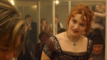 Movie still from “Titanic” (1997), directed by James Cameron – A woman with red curly hair wearing a black dress; Close Up shot, Over the shoulder angle