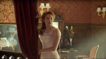 Movie still from “Titanic” (1997), directed by James Cameron – A woman standing in front of a mirror in a room; Medium shot, Low angle