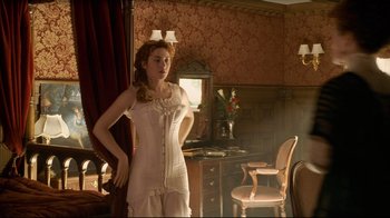 Movie still from “Titanic” (1997), directed by James Cameron – A woman in a corset standing in front of a mirror in a room; Medium shot, Over the shoulder angle