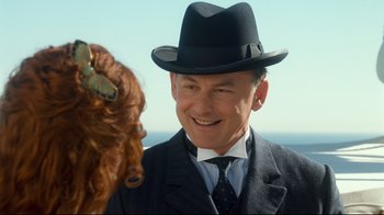 Movie still from “Titanic” (1997), directed by James Cameron – A man in a suit and a black hat is talking to a cow; Close Up shot, Over the shoulder angle