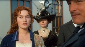 Movie still from “Titanic” (1997), directed by James Cameron – Two women and a man in a black hat; Close Up shot, Over the shoulder angle
