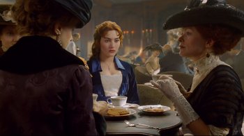Movie still from “Titanic” (1997), directed by James Cameron – A group of people sitting at a table with food; Medium shot, Over the shoulder angle