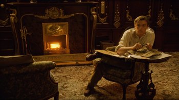 Movie still from “Titanic” (1997), directed by James Cameron – A man sitting in front of a fire place; Wide shot, High angle