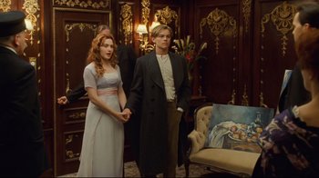 Movie still from “Titanic” (1997), directed by James Cameron – A man and a woman standing next to each other in a room; Medium shot, High angle