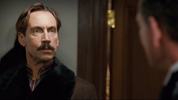 Movie still from “Titanic” (1997), directed by James Cameron – A person wearing a suit and tie; Close Up shot, Over the shoulder angle