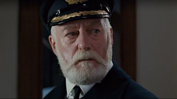 Movie still from “Titanic” (1997), directed by James Cameron – An old man with a beard wearing a hat and a tie; Close Up shot, Low angle
