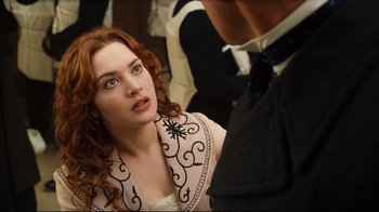Movie still from “Titanic” (1997), directed by James Cameron – A beautiful young woman with red curly hair and blue eyes; Close Up shot, Over the shoulder angle