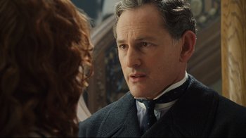 Movie still from “Titanic” (1997), directed by James Cameron – A person wearing a suit and tie; Close Up shot, Over the shoulder angle