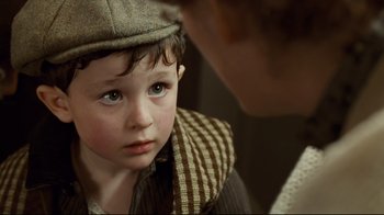 Movie still from “Titanic” (1997), directed by James Cameron – A young boy wearing a hat looking at a woman; Close Up shot, Over the shoulder angle
