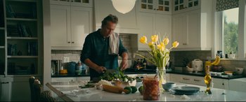 Movie still from “To All the Boys I've Loved Before” (2018), directed by Susan Johnson – A man is cutting vegetables in a kitchen; Medium shot, Low angle