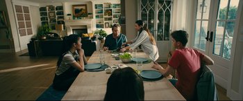 Movie still from “To All the Boys I've Loved Before” (2018), directed by Susan Johnson – A group of people sitting around a table eating food; Wide shot, Over the shoulder angle