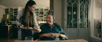 Movie still from “To All the Boys I've Loved Before” (2018), directed by Susan Johnson – A man sitting at a table with a plate of food; Medium shot, Over the shoulder angle