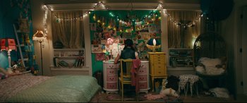 Movie still from “To All the Boys I've Loved Before” (2018), directed by Susan Johnson – A woman sitting at a desk in front of a computer; Wide shot, High angle