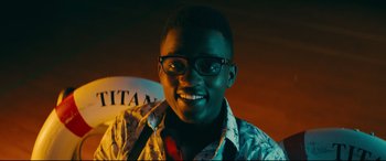 Movie still from “To All the Boys I've Loved Before” (2018), directed by Susan Johnson – A young man wearing glasses smiling for the camera; Close Up shot, Low angle