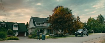 Movie still from “To All the Boys I've Loved Before” (2018), directed by Susan Johnson – A person standing in front of a house with a trash can; Extreme Wide shot, Low angle
