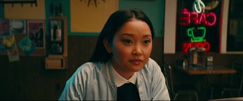 Movie still from “To All the Boys I've Loved Before” (2018), directed by Susan Johnson – A woman with long black hair wearing a tie; Close Up shot, Over the shoulder angle