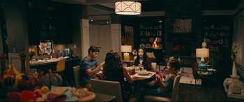 Movie still from “To All the Boys I've Loved Before” (2018), directed by Susan Johnson – A group of people sitting around a table eating food; Wide shot, High angle