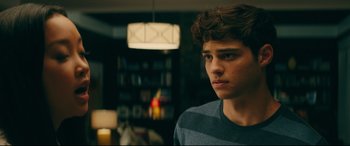 Movie still from “To All the Boys I've Loved Before” (2018), directed by Susan Johnson – A young man is looking into the distance in a room; Close Up shot, Over the shoulder angle