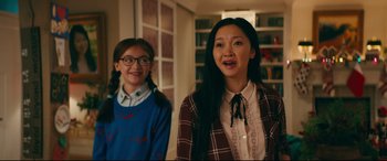 Movie still from “To All the Boys I've Loved Before” (2018), directed by Susan Johnson – Two young women standing next to each other in front of a book case; Medium shot, Over the shoulder angle