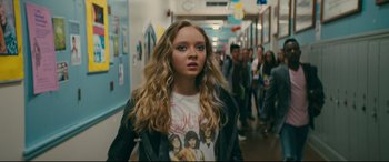 Movie still from “To All the Boys I've Loved Before” (2018), directed by Susan Johnson – A woman with long blonde hair standing in front of a group of people; Medium shot, Over the shoulder angle