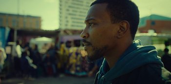 Movie still from “Top Boy” (2011), created by Ronan Bennett – A person looking away from the camera; Close Up shot, Low angle