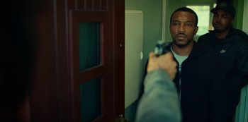 Movie still from “Top Boy” (2011), created by Ronan Bennett – A man holding a gun in front of a mirror; Close Up shot, Over the shoulder angle