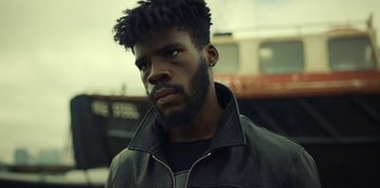 Movie still from “Top Boy” (2011), created by Ronan Bennett – A man with a beard is looking into the distance; Close Up shot, Low angle