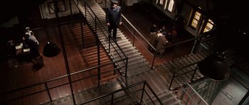 Movie still from “Shutter Island” (2010), directed by Martin Scorsese – A man standing on a set of metal stairs; Extreme Wide shot, Overhead angle