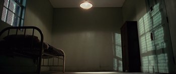 Movie still from “Shutter Island” (2010), directed by Martin Scorsese – A room with a bed and a light in it; Wide shot, High angle